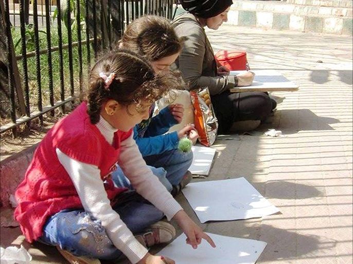 يسارع الأطفال لتعلم الرسم من الرسامين بالشارع. (تصوير خاص للرسامين بالشارع وهم يفترشون الأرض بجوارهم الأطفال يتعلمون الرسم ـ حديقة الحيوان ـ الجيزة ـ مصر ـ مايو 2017).