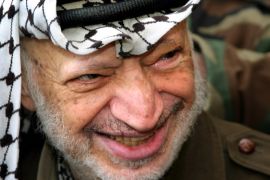 Palestinian President Yasser Arafat smiles at his headquarters in the West Bank city of Ramallah April 3, 2004. Palestinian President Yasser Arafat said on Saturday he was unmoved by a veiled threat from Israeli Prime Minister Ariel Sharon to assassinate him. Arafat says