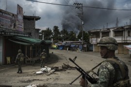 MARAWI, PHILIPPINES - JUNE 06: Soldiers patrol a street as smoke billows from a fire caused by heavy gunfights and aerial strikes on June 6, 2017 in Marawi city, Philippines. Now entering its third week, the battle for control over Marawi city between government forces and militant Maute and Abu Sayyaf groups continues inside the Islamic city in Mindanao, southern Philippines. President Rodrigo Duterte declared martial law in Mindanao right after the militants rampaged through Marawi city, which is home to some 200,000 people. (Photo by Jes Aznar/Getty Images)