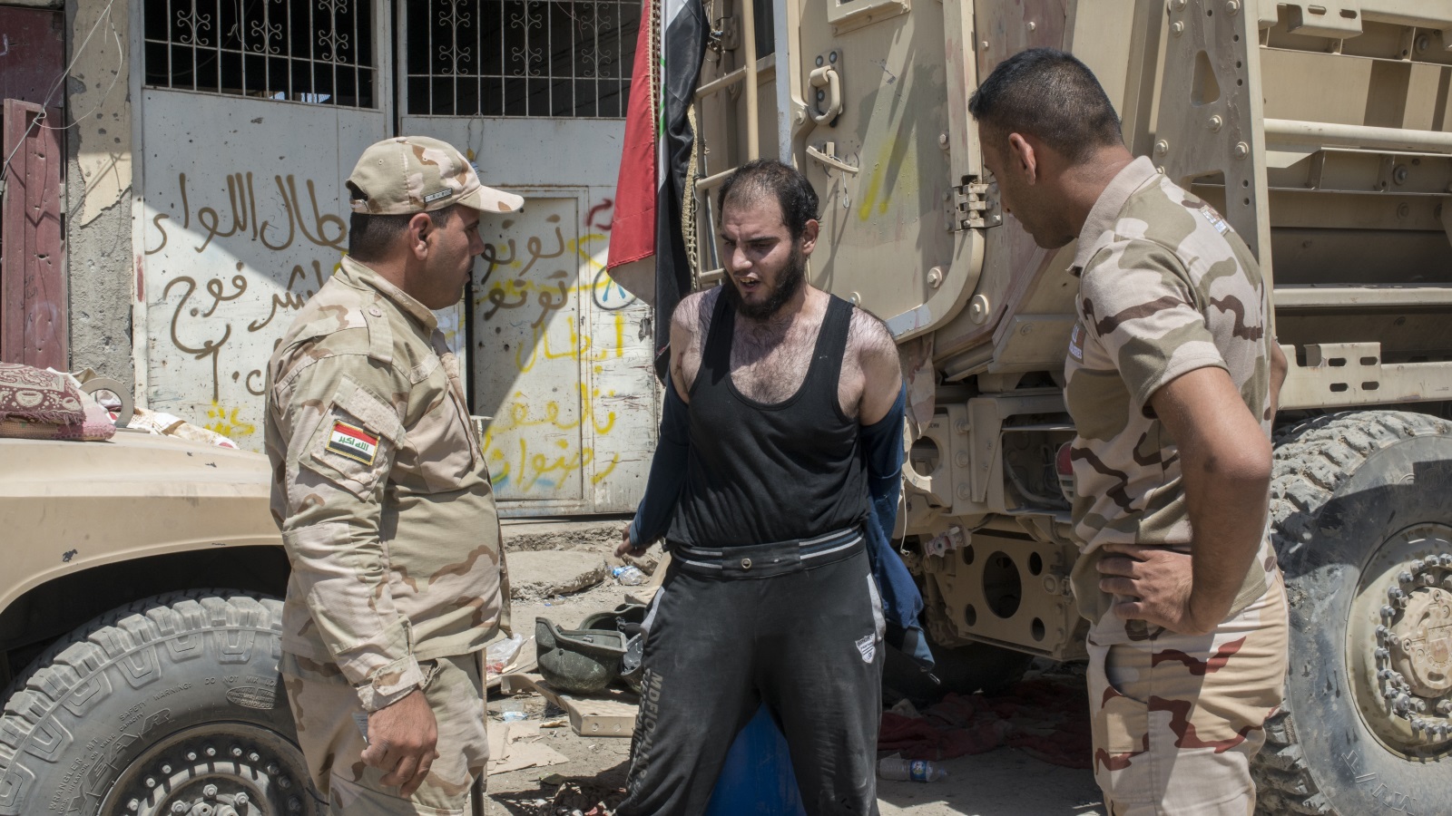 ‪جنديان عراقيان يوثقان شخصا يشتبه في أنه أحد مقاتلي تنظيم الدولة بالموصل القديمة‬ (غيتي)  