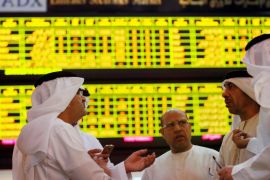 Investors speak in front of a screen displaying stock information at the Abu Dhabi Securities Exchange, United Arab Emirates June 25, 2014. REUTERS/Stringer/File Photo