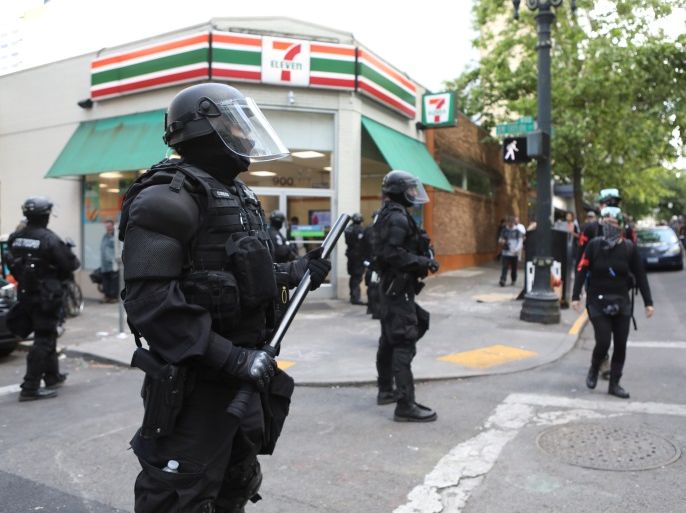 Police officers stand guard outside a corner store as competing demonstrations take place in Portland, Oregon, U.S. June 4, 2017. REUTERS/Jim Urquhart