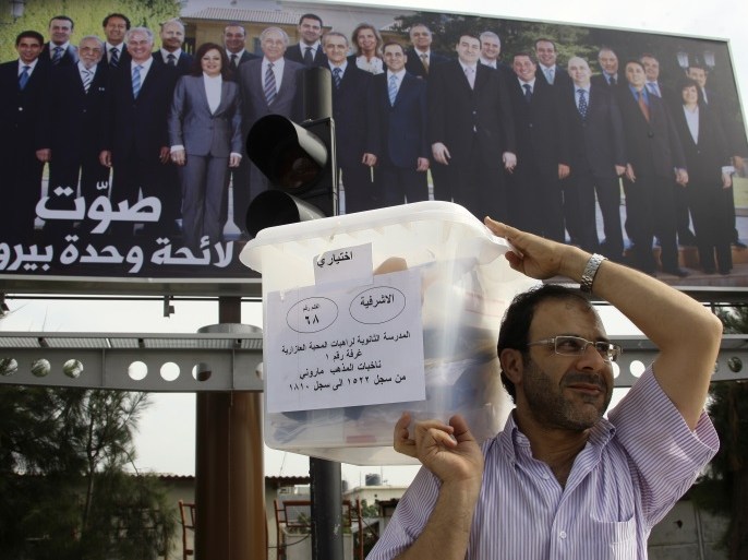 A Lebanese government election official carries a ballot box in front of a billboard depicting Lebanese candidates running in the country's municipal election, ahead of the elections in Beirut May 8, 2010.The voting is spread across four regions, each of which will vote on a Sunday in May. Beirut will be the second region to vote on Sunday, May 9, 2010. REUTERS/ Mohamed Azakir (LEBANON - Tags: ELECTIONS POLITICS)