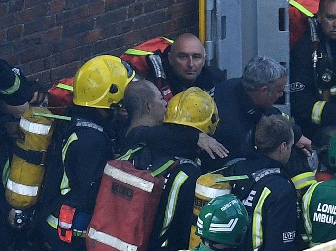 LONDON, ENGLAND - JUNE 14: A man is rescued by fire fighters after a huge fire engulfed the 24 storey residential Grenfell Tower block in Latimer Road, West London in the early hours of this morning on June 14, 2017 in London, England. The Mayor of London, Sadiq Khan, has declared the fire a major incident as more than 200 firefighters are still tackling the blaze while at least 50 people are receiving hospital treatment. (Photo by Leon Neal/Getty Images)