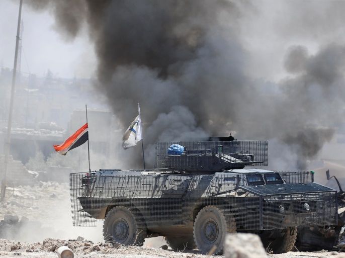 An Iraqi military armoured fighting vehicle (AFV) maneuvres past smoke billowing from a burning Iraqi military truck during fighting with Islamic State militants in Mosul's al-Zanjili's district in Iraq June 5, 2017. Picture taken June 5, 2017. REUTERS/Erik De Castro