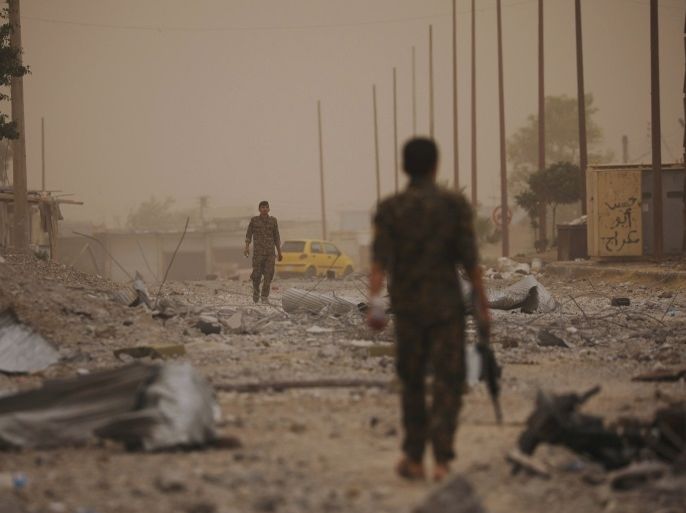 Syrian Democratic Forces (SDF) fighters walk on the rubble of a damaged street in the Raqqa's al-Sanaa industrial neighbourhood, Syria June 14, 2017. Picture taken June 14, 2017. REUTERS/Rodi Said