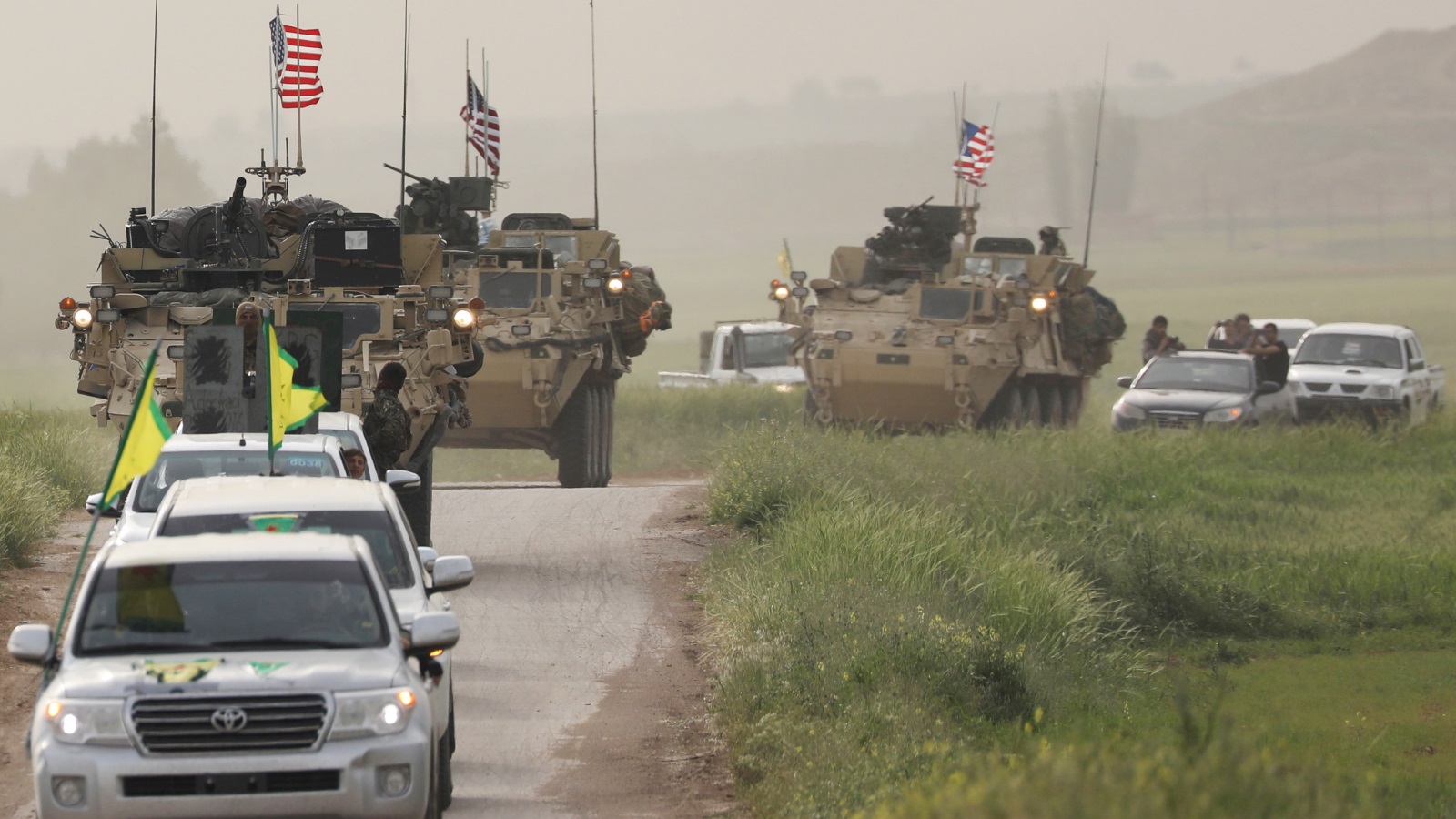 مقاتلون أكراد من وحدات حماية الشعب يتقدمون آليات عسكرية أميركية تنتشر في بلدة الدرباسية على الحدود مع تركيا (رويترز)
