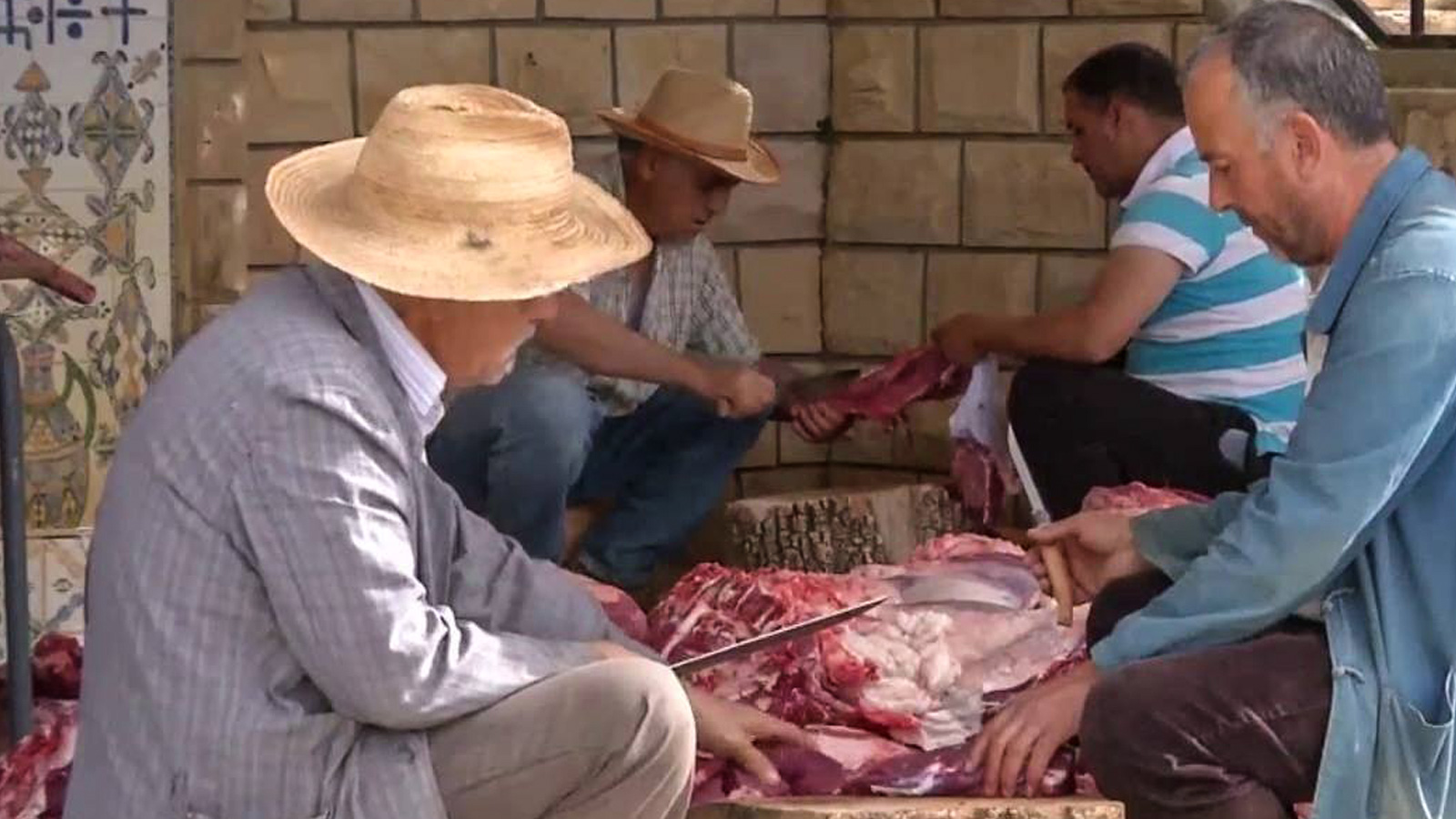 رجال من القرية يشتركون في ذبح العجول وتقطيع اللحوم لتوزيعها على السكان (الجزيرة نت)