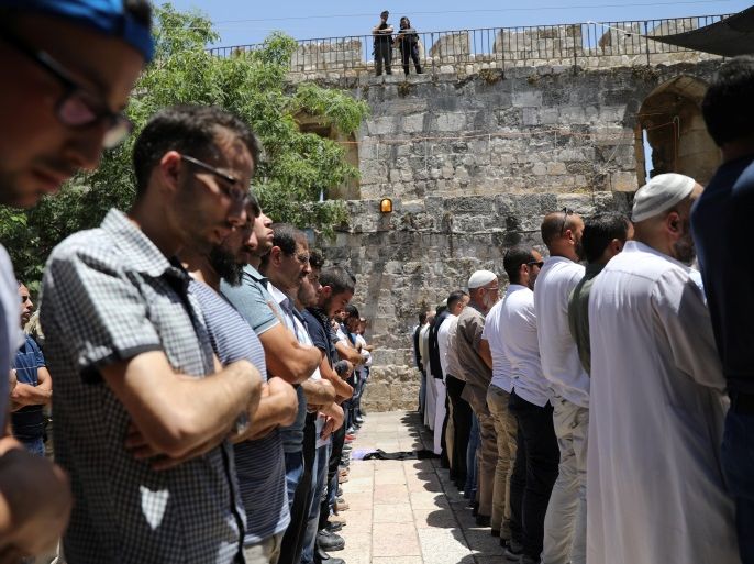 Palestinians pray as Israeli police officers look on, by newly installed metal detectors, at an entrance to the compound known to Muslims as Noble Sanctuary and to Jews as Temple Mount in Jerusalem's Old City July 16, 2017. REUTERS/Ammar Awad