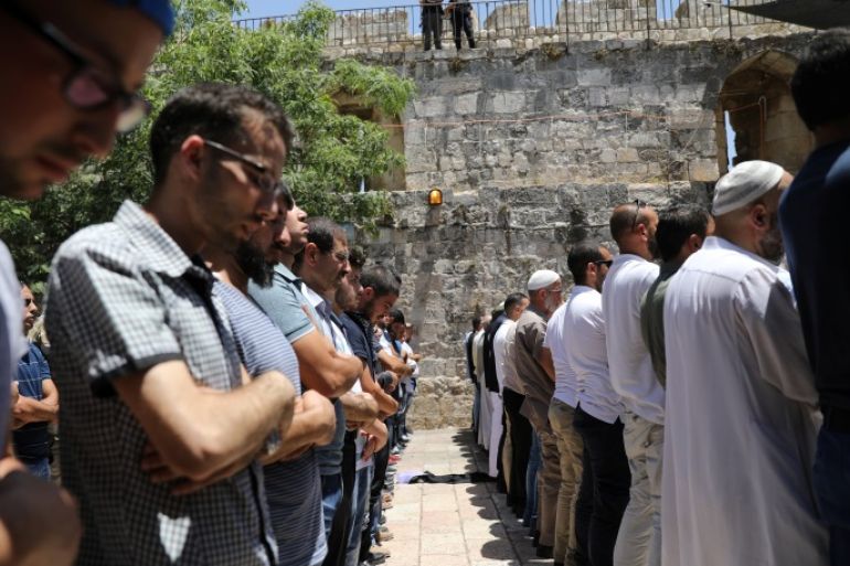 Palestinians pray as Israeli police officers look on, by newly installed metal detectors, at an entrance to the compound known to Muslims as Noble Sanctuary and to Jews as Temple Mount in Jerusalem's Old City July 16, 2017. REUTERS/Ammar Awad