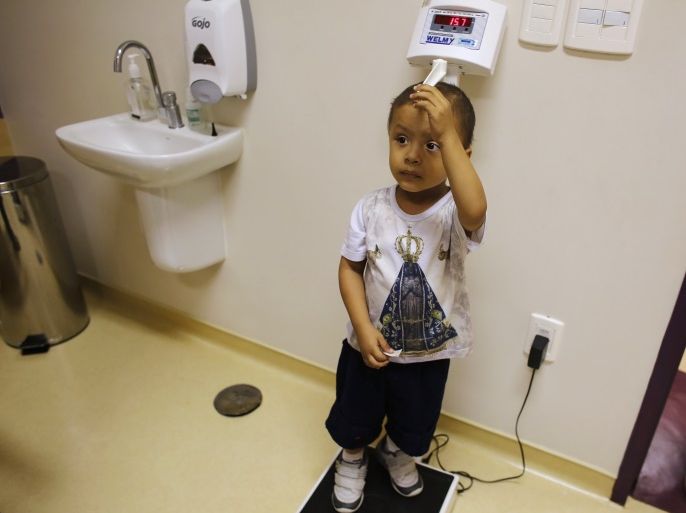 Rafael Freitas, a three-year-old cancer patient, wearing a T-shirt with an image of Brazil's national saint Our Lady of Aparecida, takes his measurements after receiving an injection, in the Hospital de Cancer in Barretos, Sao Paulo state March 3, 2015. Rafael was diagnosed with Neuroblastoma one year ago, a disease in which malignant cancer cells form in nerve tissue of adrenal glands. Every day in his hospital bedroom in the interior of Sao Paulo, he practices the motions of Holy Communion, in the hope of one day raising his cup towards the Sistine Chapel. Picture taken March 3, 2015. REUTERS/Nacho Doce (BRAZIL - Tags: HEALTH RELIGION SOCIETY)
