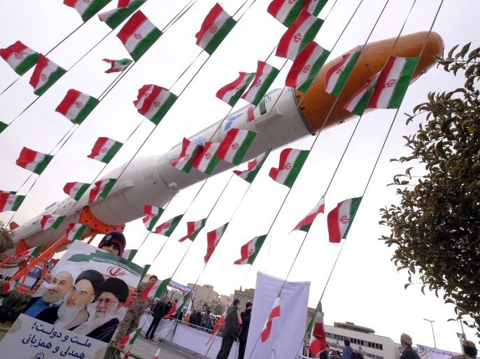 A boy holding a placard with pictures of (L-R) President Hassan Rouhani, the late founder of the Islamic Revolution Ayatollah Ruhollah Khomeini, and Iran's Supreme Leader Ayatollah Ali Khamenei, poses for camera in front of a model of Simorgh satellite-carrier rocket during a ceremony marking the 37th anniversary of the Islamic Revolution, in Tehran February 11, 2016. REUTERS/Raheb Homavandi/TIMAATTENTION EDITORS - THIS IMAGE WAS PROVIDED BY A THIRD PARTY. FOR EDITORIAL USE ONLY.