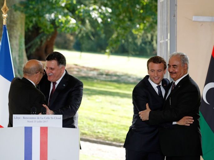 French President Emmanuel Macron embraces General Khalifa Haftar (R), commander in the Libyan National Army (LNA) as French Europe and Foreign Minister Jean-Yves Le Drian (L) embraces Libyan Prime Minister Fayez al-Sarraj (2ndL) after talks over a political deal to help end Libya’s crisis in La Celle-Saint-Cloud near Paris, France, July 25, 2017. REUTERS/Philippe Wojazer