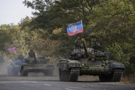 In this photo taken on Wednesday, Oct.  21, 2015, Russia-backed rebel tanks with a flag of the self-proclaimed Donetsk People's Republic, move to storage during the withdrawal of weapons near Novoazovsk, eastern Ukraine. The fighting has subsided, but Donetsk is quickly sinking into the past, a shabby Soviet-like state of empty streets and deprivation. Huge portraits of Josef Stalin hanging in the city center only reinforce the impression of failure.  (AP Photo/Max Black)