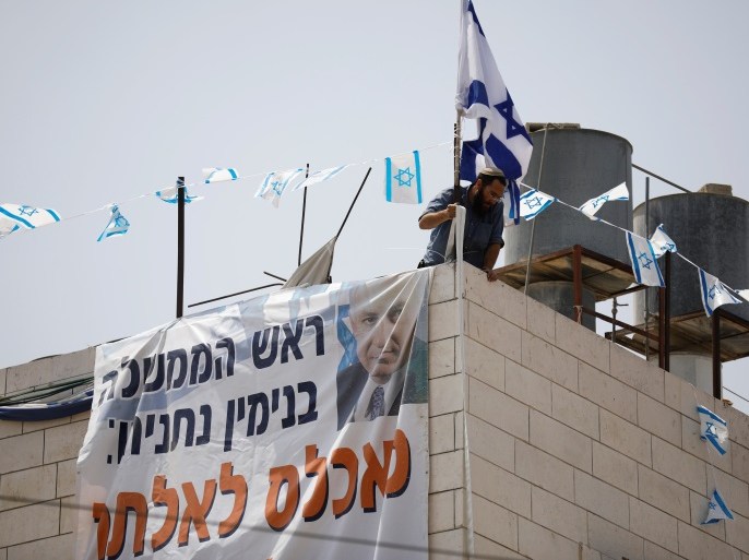A Jewish settler adjusts a banner to a disputed building where about a hundred hard-line Jewish settlers have hunkered down, in the West Bank city of Hebron, July 26, 2017. The banner with Hebrew writing reads: 'Prime Minister Benjamin Netanyahu, populate the Patriarchs House immediately'. REUTERS/Amir Cohen