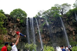 A tourist lifts up a boy as they visit waterfalls at Ayn Athum in Salalah, Dhofar province, Oman August 23, 2016. Picture taken August 23, 2016. REUTERS/Ahmed Jadallah