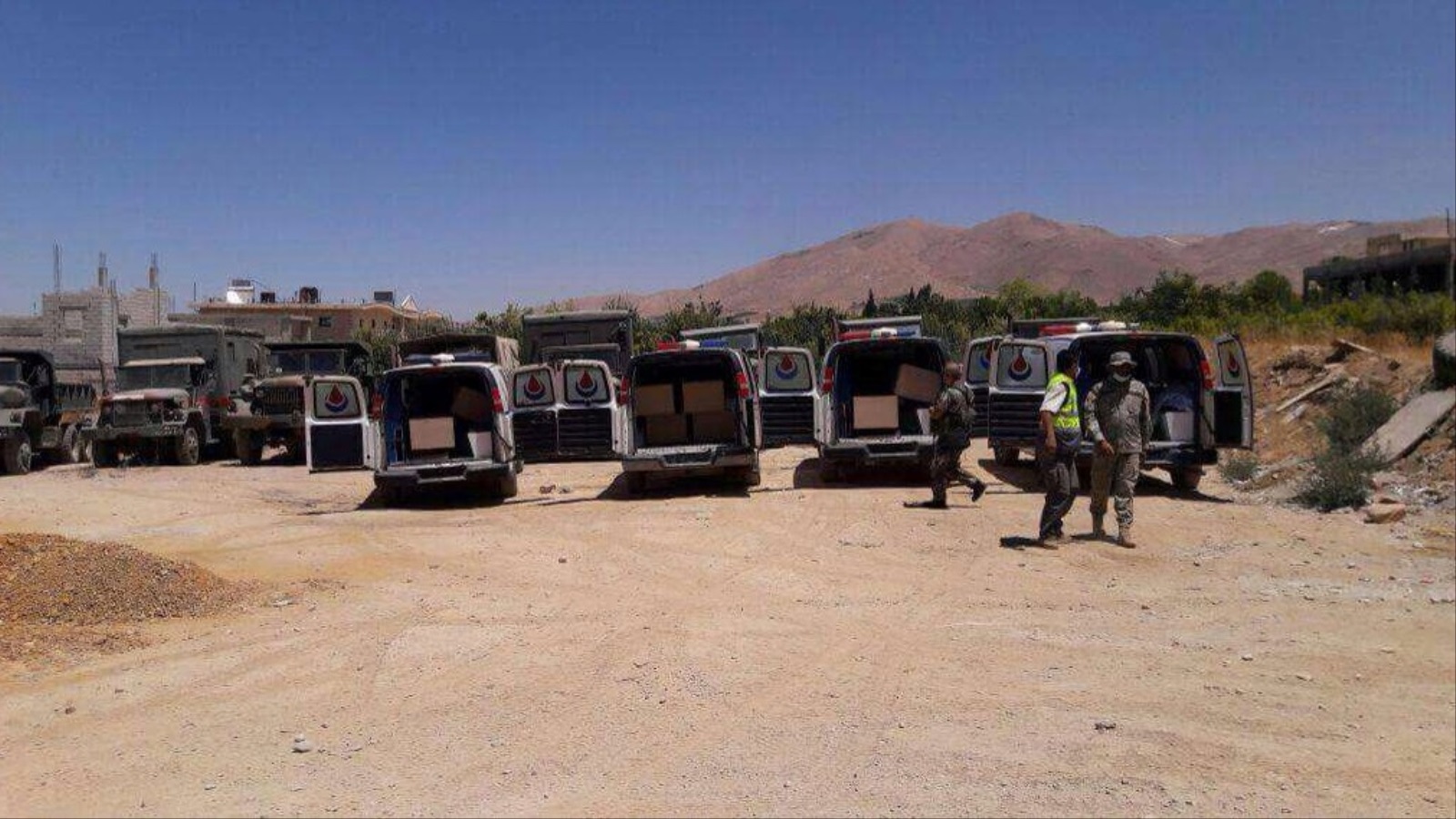 ‪عربات إسعاف تحمل جثامين مقاتلي هيئة تحرير الشام وقد تم تسليمها أمس ضمن المرحلة الأولى للاتفاق‬ (رويترز)