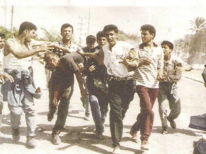 الموسوعة - مدنييون ينقلون الشهيد أحمد النجار بعد إصابته في رأسه على حاجز غوش بتاريخ 26/9/1996