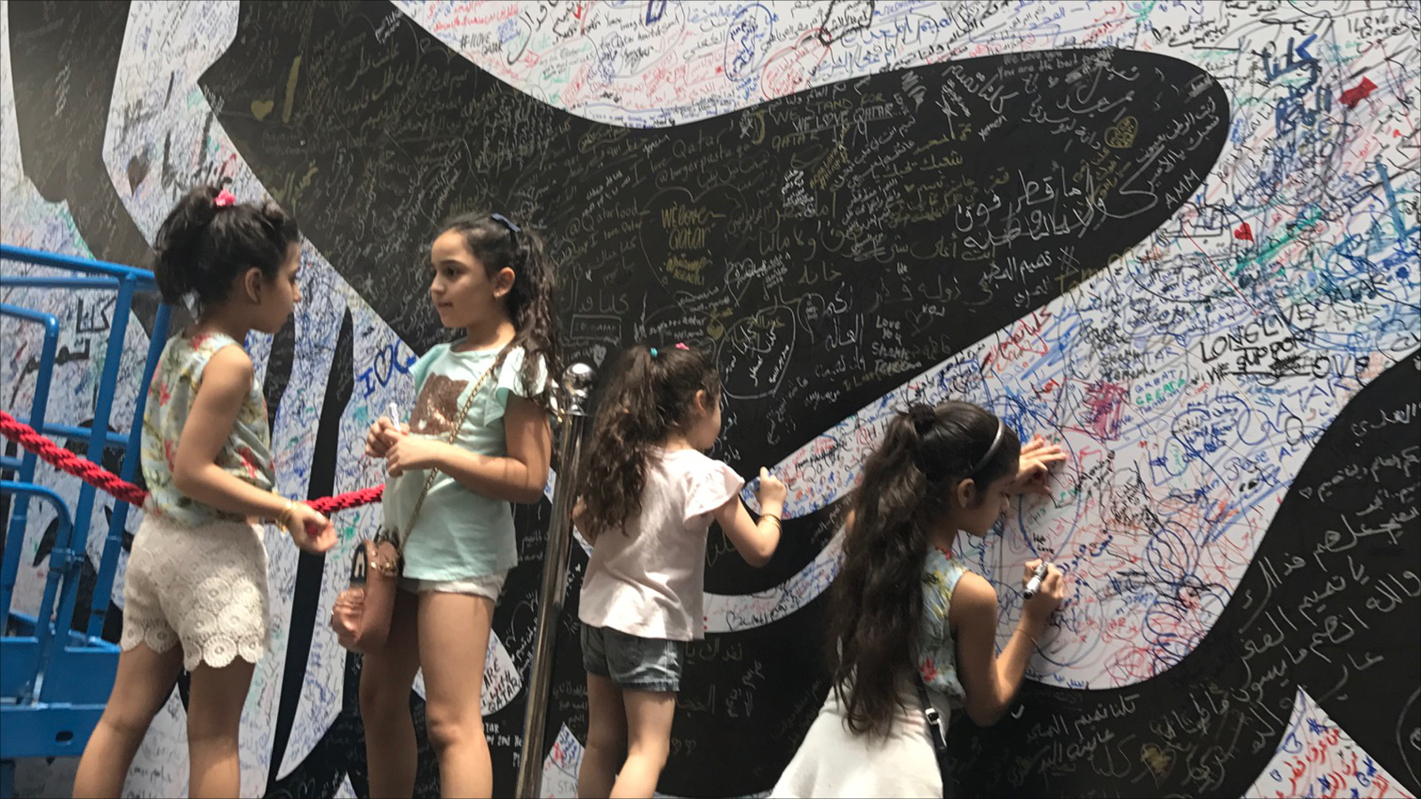 حتى الأطفال يشاركون في حملة التوقيعات على جدارية تميم المجد (الجزيرة نت) 