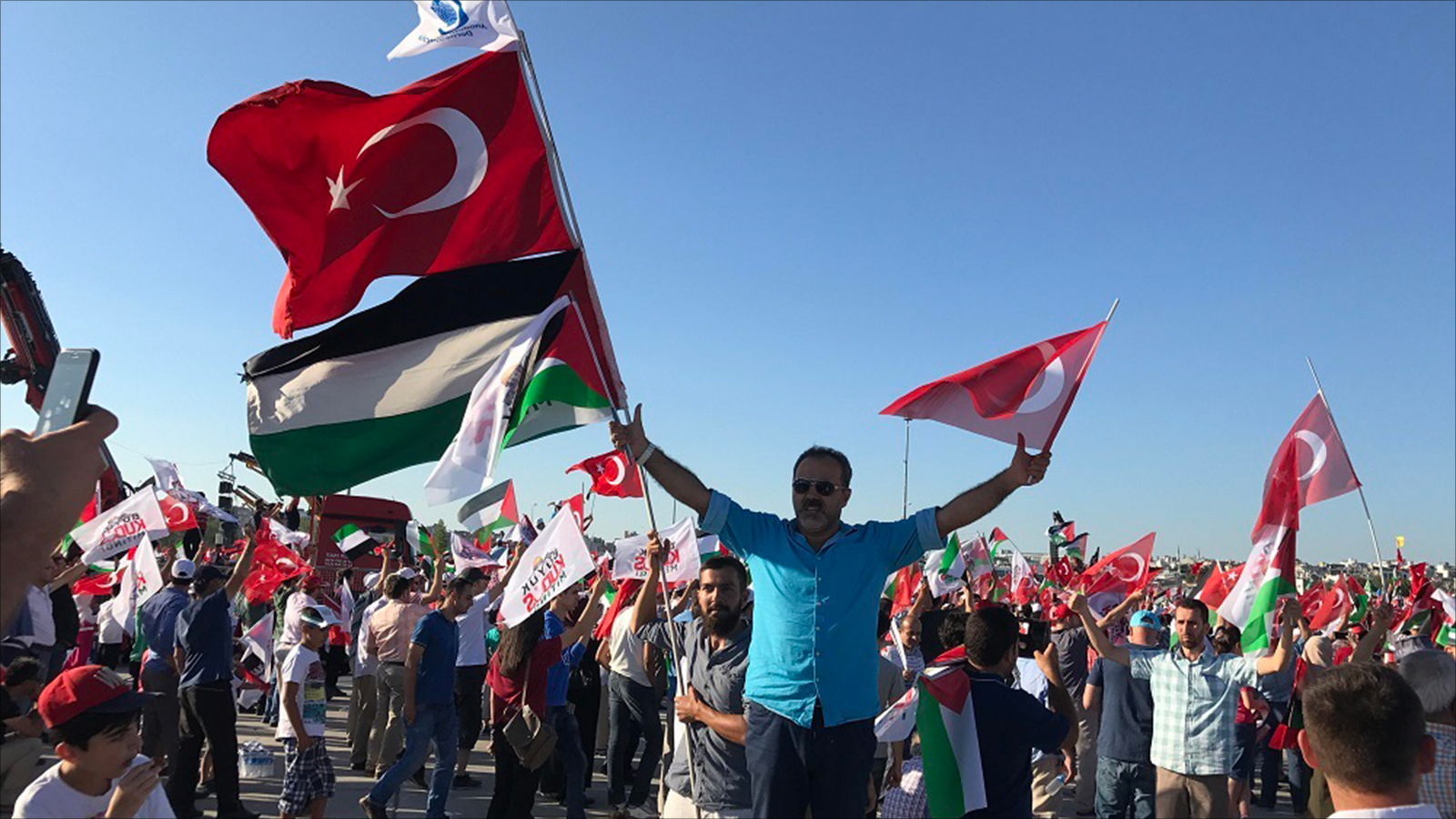 مواطن تركي يحمل أعلام فلسطين وتركيا في التجمع الحاشد