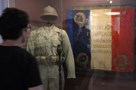 A visitor looks at a soldier costume and a French national flag which reads