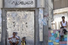 People sit by the closed door of a government bank in Yemen's southern port city of Aden September 27, 2015. As Gulf-backed forces assemble in Marib province east of Sanaa ahead of a widely expected thrust towards the Houthi-held capital, the fate of Aden and its hinterland may offer a glimpse at whether some form of central government can be resurrected. To match Insight YEMEN-SECURITY/ADEN REUTERS/Faisal Al Nasser