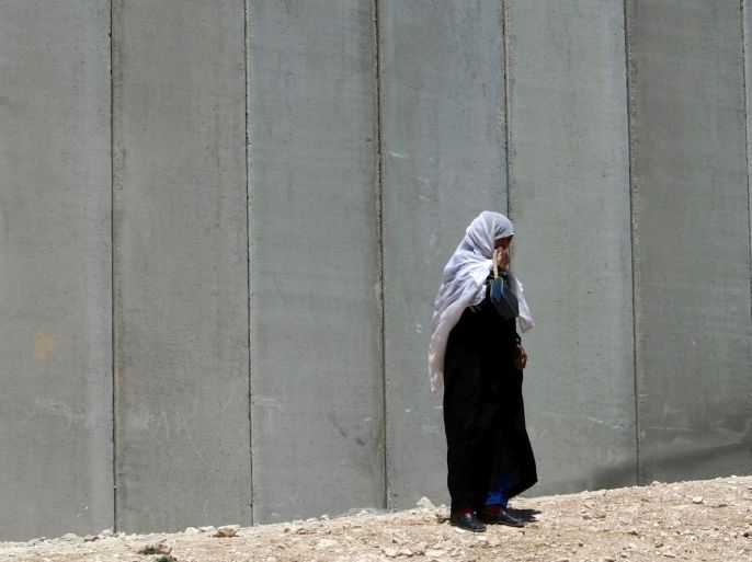 A Palestinian woman walks along the controversial Israeli barrier in Shuafat in the West Bank, near Jerusalem June 14, 2009. Israeli Prime Minister Benjamin Netanyahu gives a major policy speech on Sunday and will address the worst public rift with Washington in a decade over Jewish settlement building and Palestinian statehood. REUTERS/Ammar Awad (WEST BANK POLITICS CONFLICT)