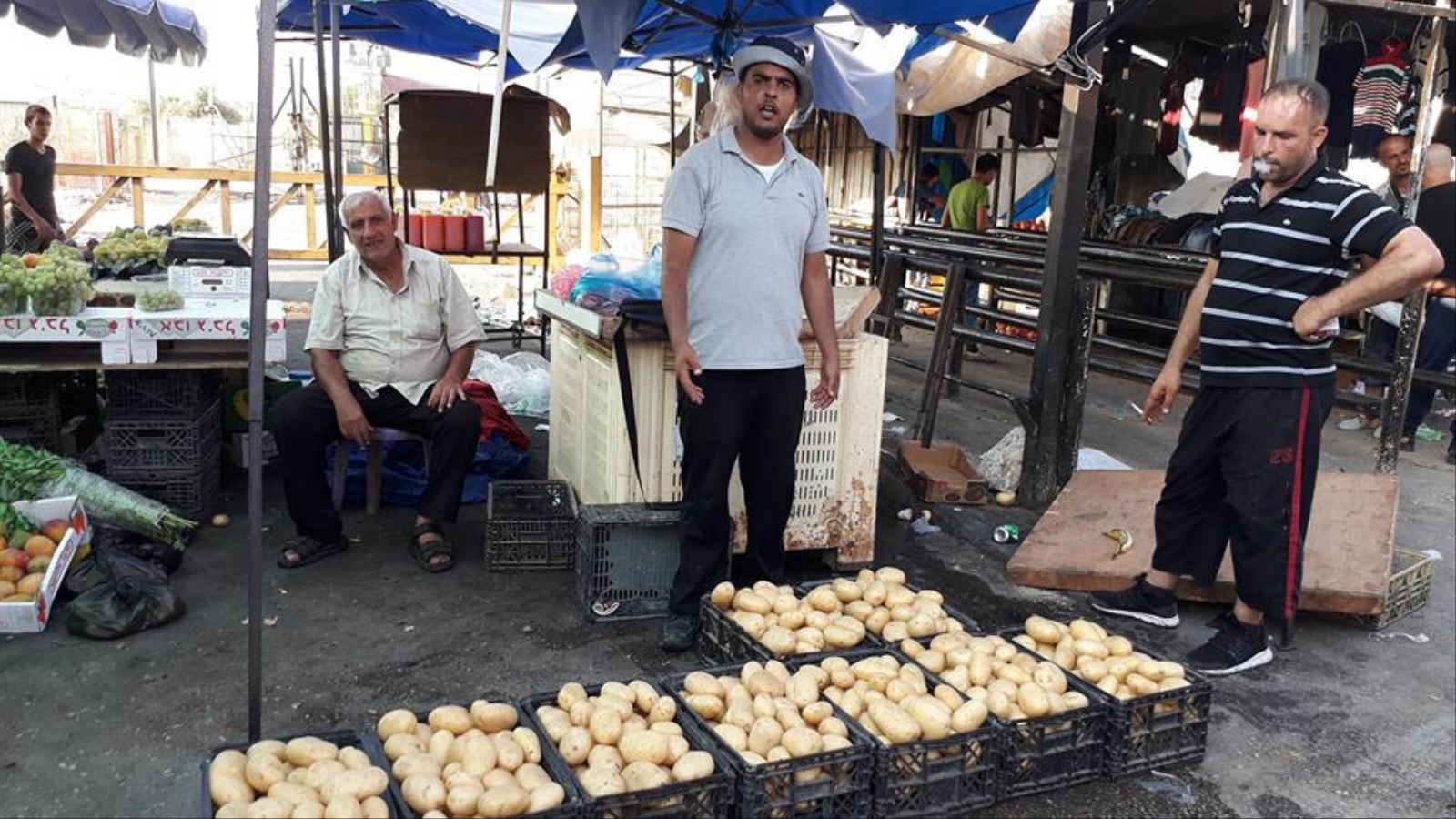 محمد قديح (وسط) يبيع الخضر عند حاجز قلقيلية 