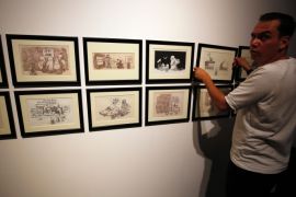 A man hangs cartoons by Palestinian caricaturist Naji al-Ali, who was assassinated in London 22 July 1987, during a media tour ahead of the 'Jerusalem Lives' exhibition at the Palestinian Museum on August 26, 2017, in the West Bank town of Birzeit, near Ramallah.The exhibition is scheduled to open on August 27 until December 15. / AFP PHOTO / ABBAS MOMANI / RESTRICTED TO EDITORIAL USE, MANDATORY CREDIT OF THE ARTIST, 'NAJI AL-ALI' TO ILLUSTRATE THE EVENT AS SPECIFIE
