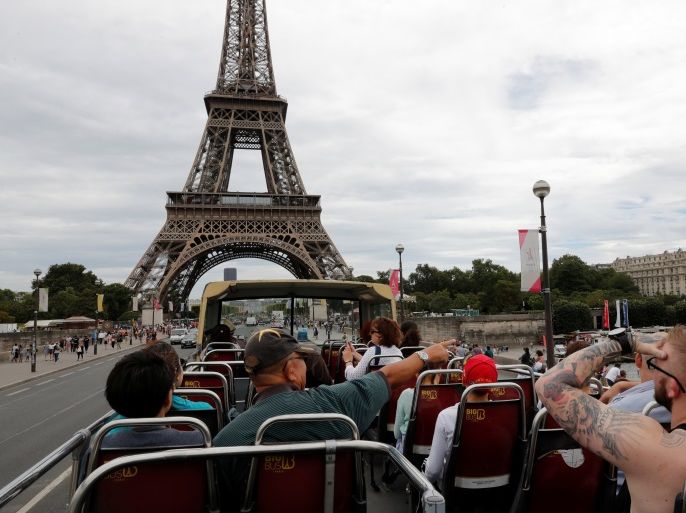 People ride an open double-decker tour bus that crosses a bridge near the Eiffel Tower in Paris, France, August 2, 2017. REUTERS/Philippe Wojazer