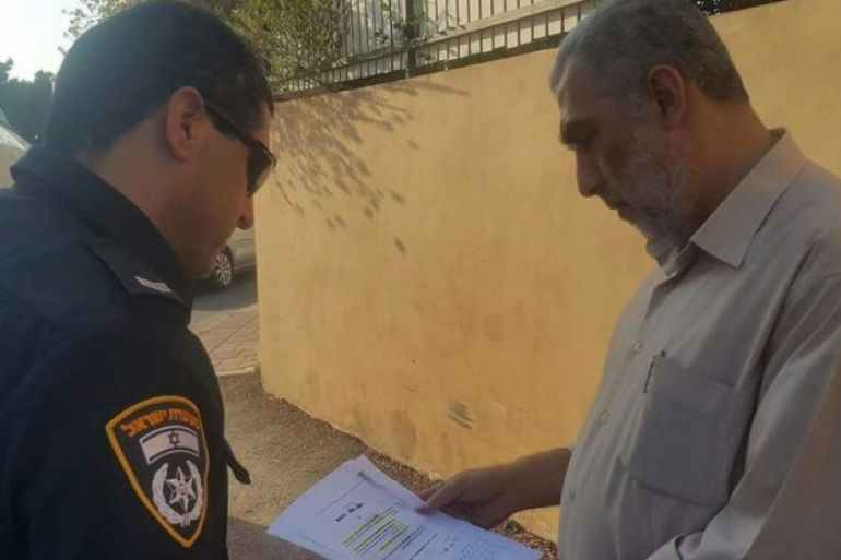 شرطي إسرائيلي يسلم الشيخ كمال الخطيب قرارا بمنع دخوله لمدينة القدس والأقصى- ناشطون.jpg