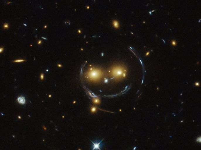 The galaxy cluster SDSS J1038+4849 is pictured in this undated handout image taken with the NASA/ESA Hubble Space Telescope. As a result of the phenomenon of gravitational lensing, it seems to be smiling. In the case of this