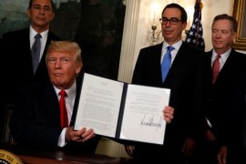 U.S. President Donald Trump, flanked by U.S. Representative Darrell Issa (R-CA) (L), Treasury Secretary Steven Mnuchin (3rd R), U.S. Trade Representative Robert Lighthizer (2nd R) and Commerce Secretary Wilbur Ross (R), finishes signing a memorandum directing the U.S. Trade Representative to complete a review of trade issues with China at the White House in Washington, U.S. August 14, 2017. REUTERS/Jonathan Ernst