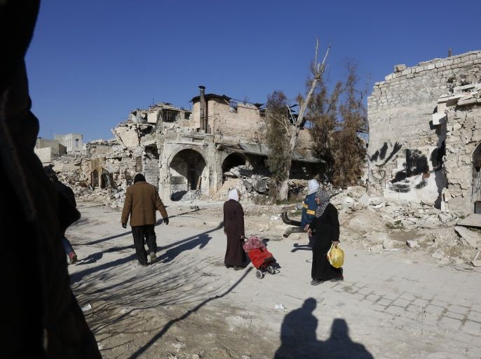 Citizens of Aleppo walk through a severely damaged part of Al-Hatab Square in the old quarter of Aleppo