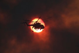 A firefighting helicopter flies in front of the setting sun as a wildfire burns near the village of Kapandriti, north of Athens, Greece, August 15, 2017. REUTERS/Alkis Konstantinidis