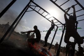 Young Palestinians swing across monkey bars over fire during a military-style exercise at a Hamas summer camp in Rafah in the southern Gaza Strip July 27, 2017. REUTERS/Ibraheem Abu Mustafa