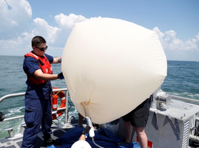 US Coast Guard fireman Justin Spurlin (L) helps hold a balloon during a test launch for the Space Grant Ballooning Project in preparations for Monday's solar eclipse on board a US Coast Guard response boat at sea near Charleston, South Carolina, U.S. August 17, 2017. Location coordinates for this image are 32º41' 975