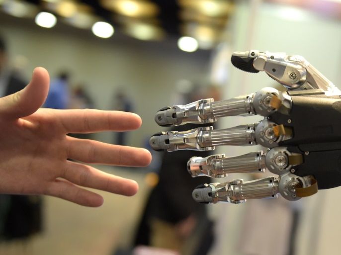 A man moves his hand toward SVH (Servo Electric 5 Finger Gripping Hand) automated hand made by Schunk during the 2014 IEEE-RAS International Conference on Humanoid Robots in Madrid on November 19, 2014. The conference theme 'Humans and Robots Face-to-Face' confirms the growing interest in the field of human-humanoid interaction and cooperation, especially during daily life activities in real environments. AFP PHOTO/ GERARD JULIEN (Photo credit should read GERAR