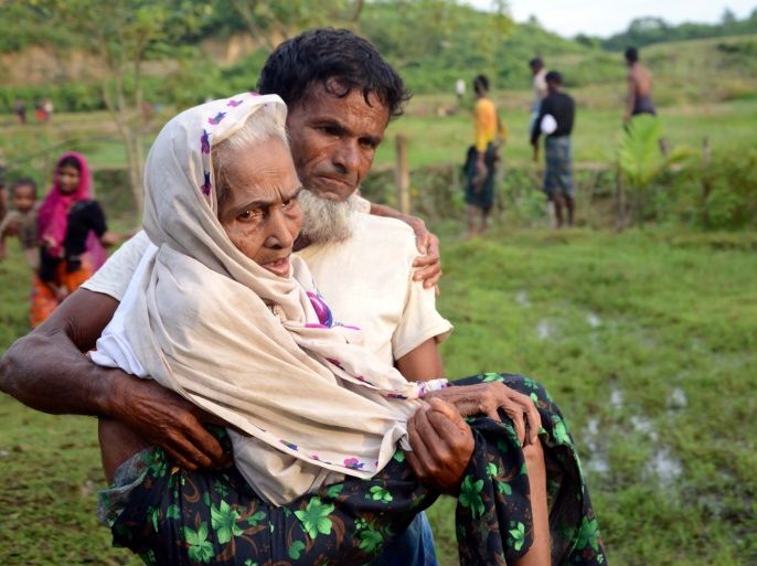 This August 30, 2017 photo shows a Rohingya man carrying his mother in Ukhiya after crossing the Bangladesh-Myanmar border.The International Organization for Migration said August 30 that at least 18,500 Rohingya had crossed into Bangladesh since fighting erupted in Myanmar's neighbouring Rakhine state six days earlier. / AFP PHOTO / Suzauddin Rubel (Photo credit should read SUZAUDDIN RUBEL/AFP/Getty Images)