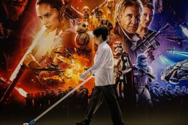 TOPSHOT - A cleaner walks past a poster advertising 'Star Wars: The Force Awakens' in Hong Kong on December 17, 2015. It may be one of the most hyped films of all time, but 'Star Wars: The Force Awakens' opened on December 16 to ecstatic reviews from both fans and critics. AFP PHOTO / ANTHONY WALLACE / AFP / ANTHONY WALLACE (Photo credit should read ANTHONY WALLACE/AFP/Getty Images)