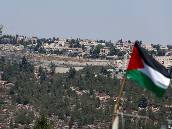 A Palestinian flag is seen in front of the Jewish settlement of Gilo, in the West Bank village of Walajeh, near Bethlehem, August 18, 2017. REUTERS/Mussa Qawasma