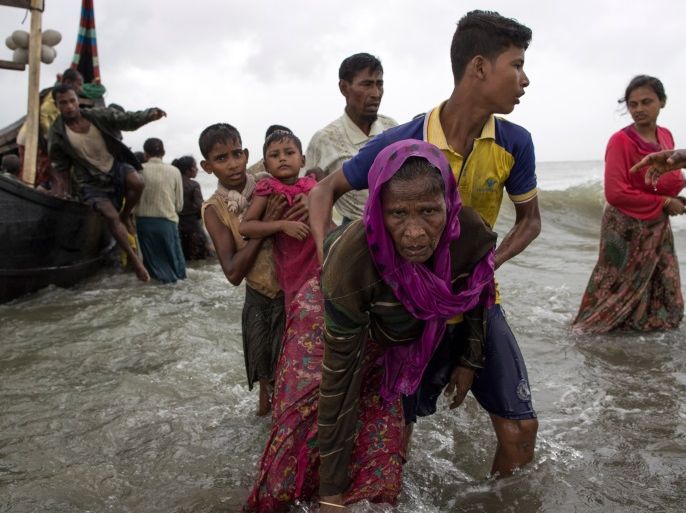 DAKHINPARA, BANGLADESH - SEPTEMBER 12:  A young Rohingya man carries an elderly woman, after the wooden boat they were travelling on from Myanmar, crashed into the shore and tipped everyone out on September 12, 2017 in Dakhinpara, Bangladesh. Recent reports have suggested that around 290,000 Rohingya have now fled Myanmar after violence erupted in Rakhine state. The 'Muslim insurgents of the Arakan Rohingya Salvation Army' have issued statement that indicates that they are to observe a cease fire, and have asked the Myanmar government to reciprocate.  (Photo by Dan Kitwood/Getty Images)