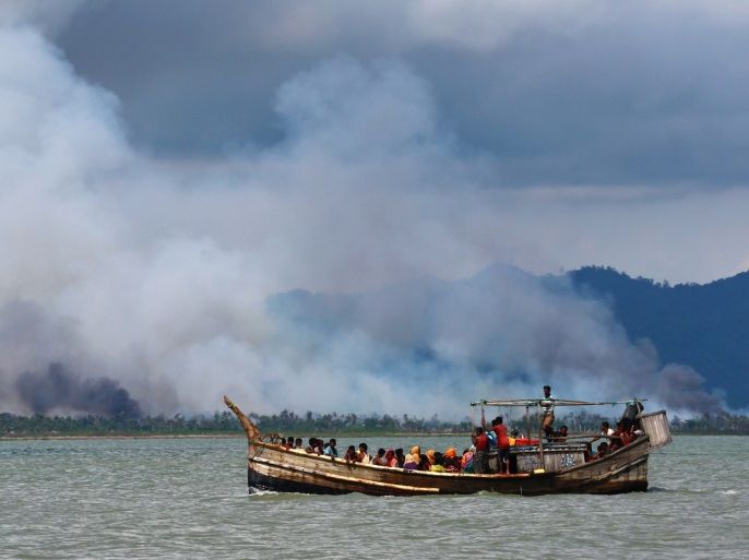 Smoke is seen on Myanmar's side of border as a boat carrying Rohingya refugees arrives on shore after crossing the Bangladesh-Myanmar border through the Bay of Bengal, in Shah Porir Dwip, Bangladesh September 11, 2017. REUTERS/Danish Siddiqui