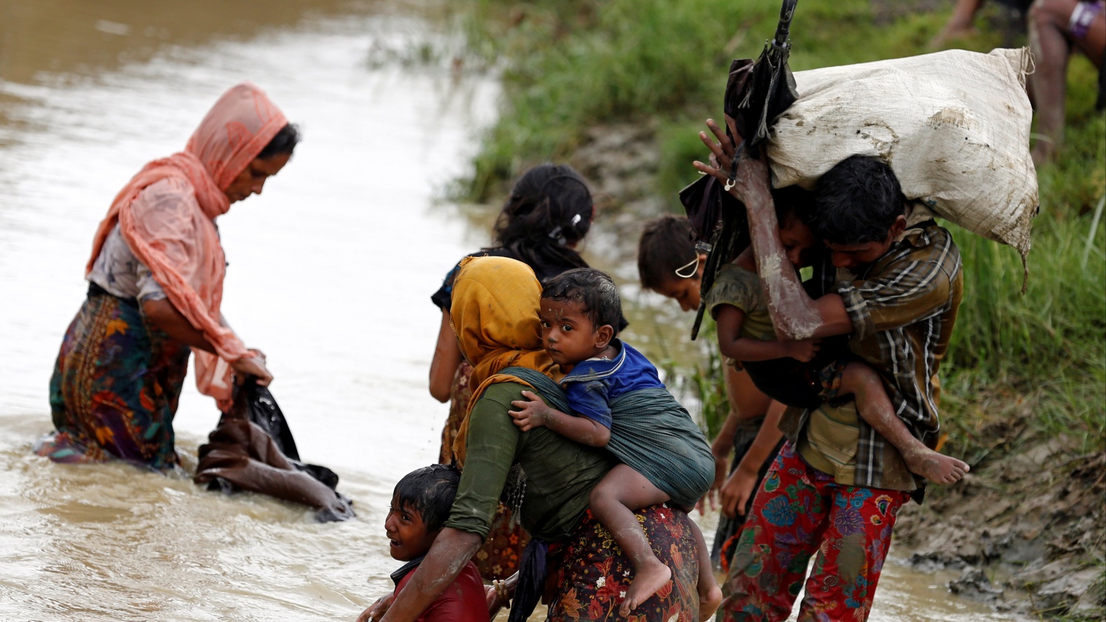‪فارون من أقلية الروهينغا يعبرون قناة مائية باتجاه بنغلاديش هربا من أعمال العنف بميانمار‬ (رويترز)