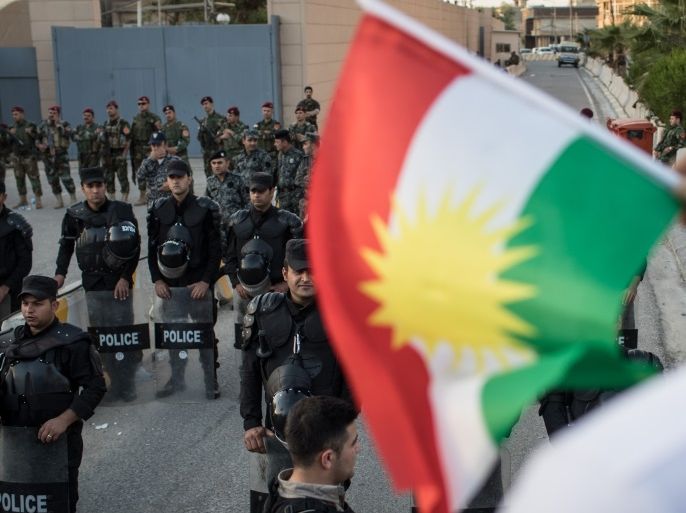 ERBIL, IRAQ - OCTOBER 21: A man holds a Kurdish flag in front of police and security forces during a protest outside the US Consulate on October 21, 2017 in Erbil, Iraq. The demonstration was held to protest against the escalating crisis with Baghdad and to call on the international community for assistance. (Photo by Chris McGrath/Getty Images)