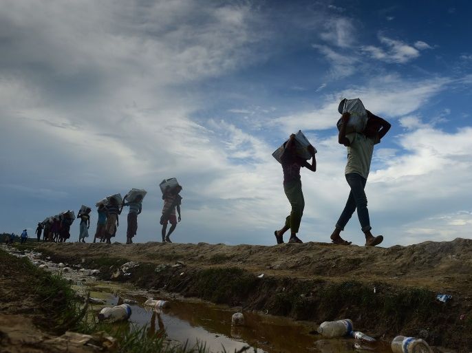 Bangladeshi workers carry relief materials for Rohingya refugees stranded in the no man's land area between Bangladesh and Myanmar, in the Palongkhali area near Ukhia on October 18, 2017.Almost 600,000 Rohingya refugees have reached Bangladesh since August, fleeing violence in Myanmar's Rakhine state, where the UN has accused troops of waging an ethnic cleansing campaign against them. / AFP PHOTO / MUNIR UZ ZAMAN (Photo credit should read MUNIR UZ ZAMAN/AFP/Get