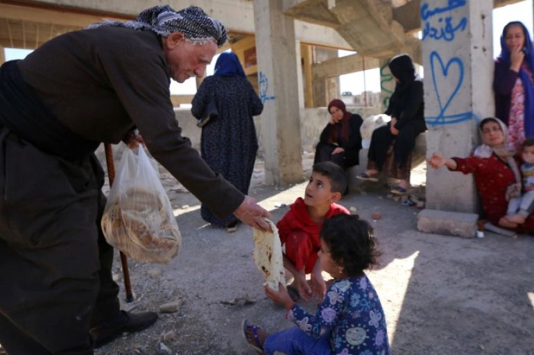 An Iraqi Kurdish man from Arbil distributes bread to a family fleeing violence in the northern Kirkuk province on October 19, 2017 at an unfinished housing project where displaced people are taking shelter in Arbil, the capital of the autonomous Kurdish region of northern Iraq. / AFP PHOTO / SAFIN HAMED (Photo credit should read SAFIN HAMED/AFP/Getty Images)