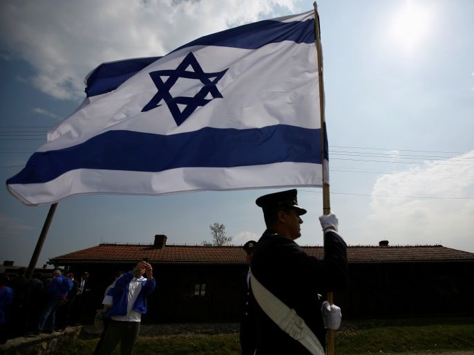 A man holds an Israeli flag in the former Nazi death camp of Auschwitz-Birkenau (Auschwitz II) as thousands of people, mostly youth from all over the world gathered for the annual