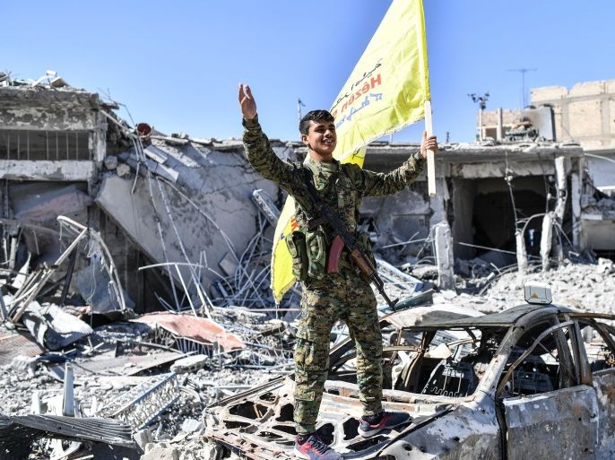 A member of the Syrian Democratic Forces (SDF), backed by US special forces, holds up their flag at the iconic Al-Naim square in Raqa on October 17, 2017.US-backed forces said they had taken full control of Raqa from the Islamic State group, defeating the last jihadist holdouts in the de facto Syrian capital of their now-shattered 'caliphate'. / AFP PHOTO / BULENT KILIC (Photo credit should read BULENT KILIC/AFP/Getty Images)