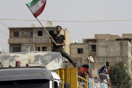 A Syrian man holds the Iranian flag as a convoy carrying aid provided by Iran arrives in the eastern city of Deir Ezzor on September 20, 2017 while Syrian government forces continue to press forward with Russian air cover in the offensive against Islamic State group jihadists across the province.Two separate offensives are under way against the jihadists in the area -- one by the US-backed Syrian Democratic Forces, the other by Russian-backed government forces. The Syri